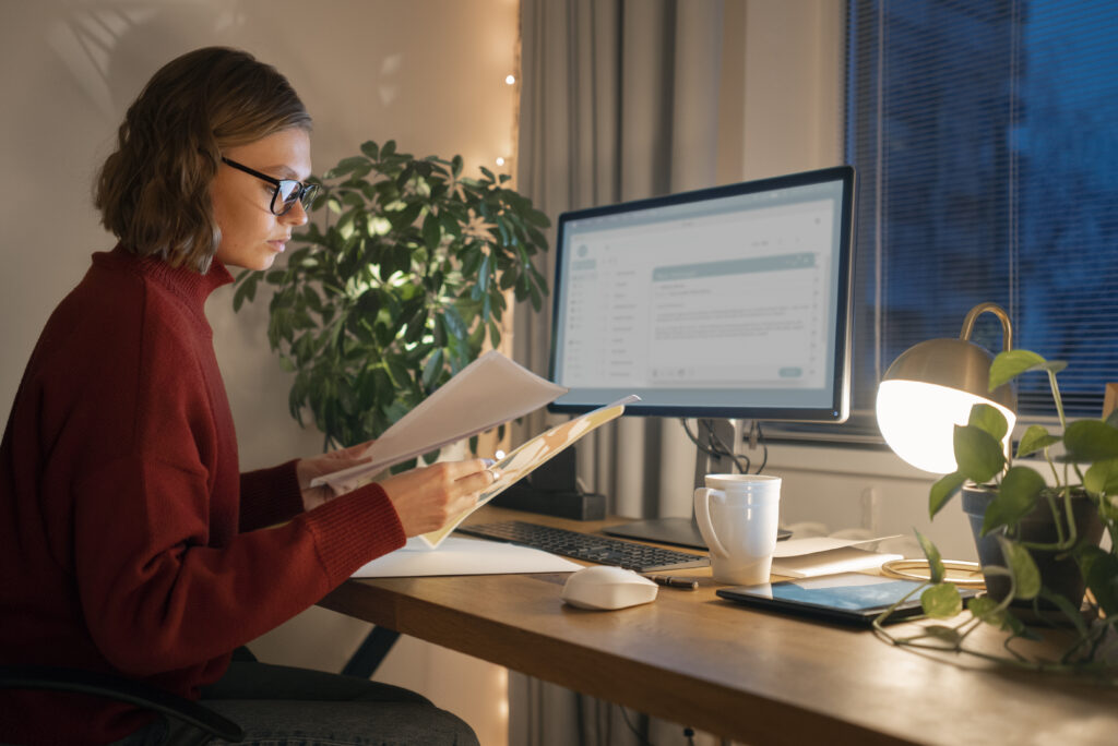 Bookkeeper working late at desk with paperwork and computer, representing accurate and reliable data entry services.
